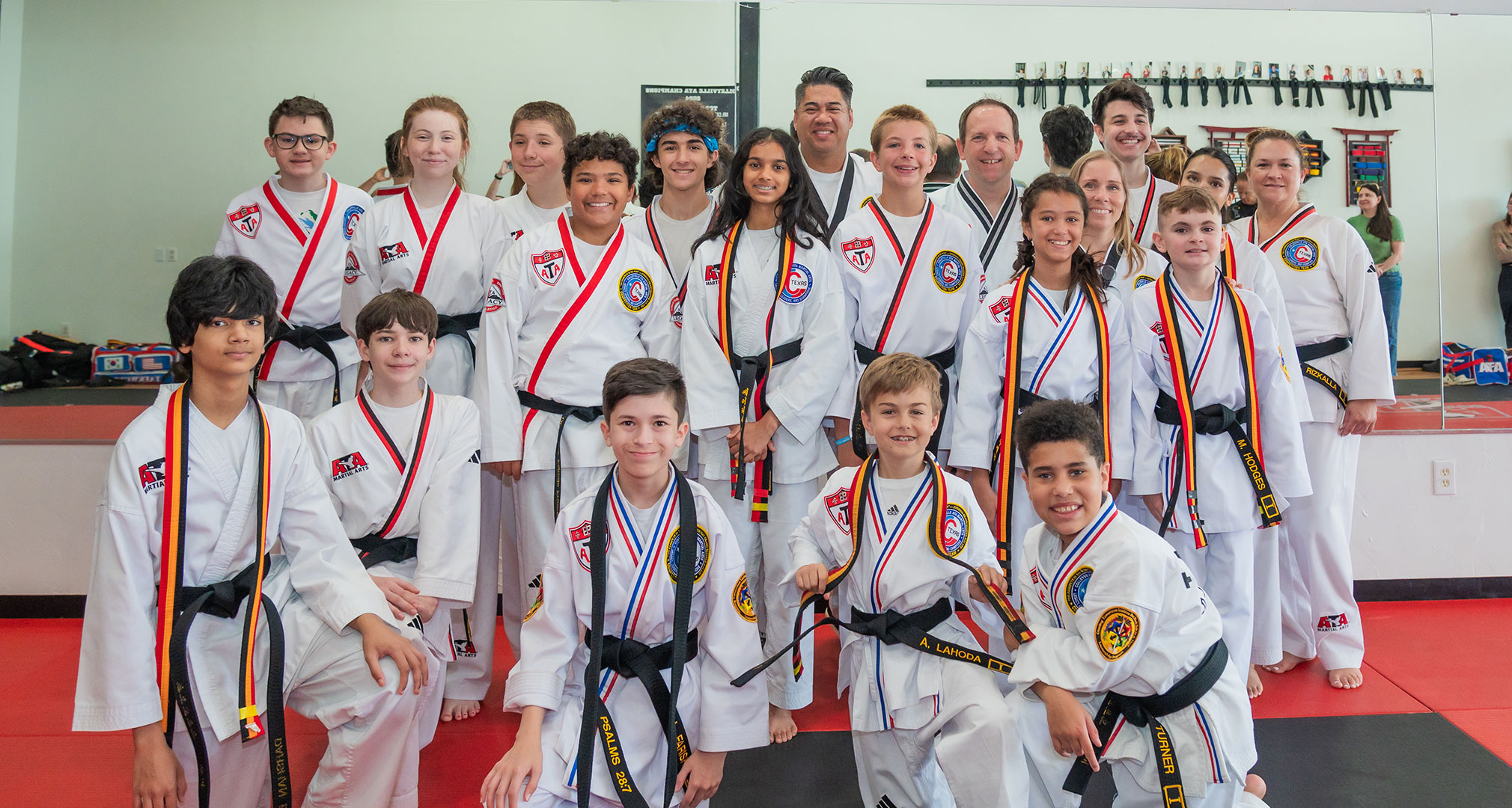 Colleyville ATA students and instructors posed together on the red mats in white uniforms.