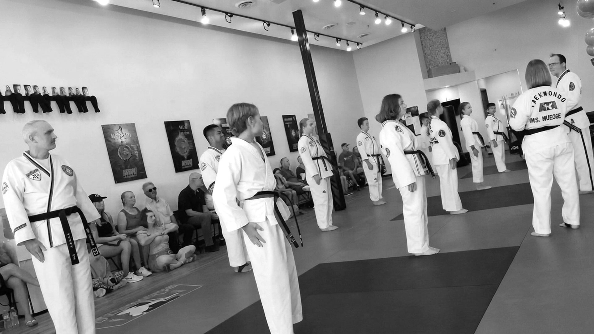 Students stand in line on the mat while Chief Instructor Susan Muegge watches the class.